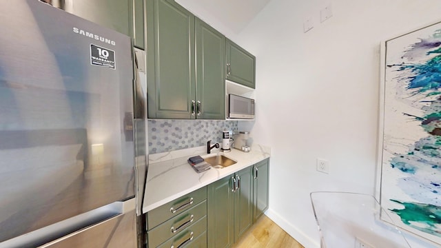 kitchen featuring appliances with stainless steel finishes, sink, light hardwood / wood-style flooring, and green cabinetry