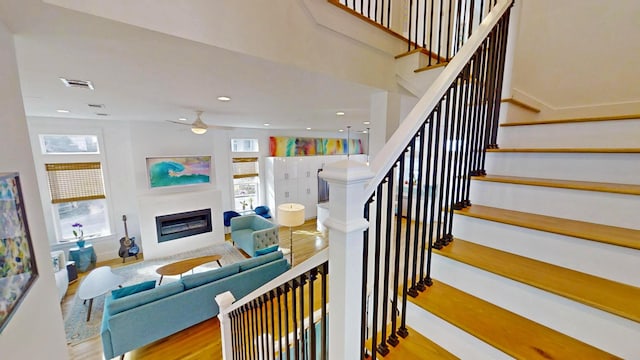 stairway with hardwood / wood-style floors and ceiling fan