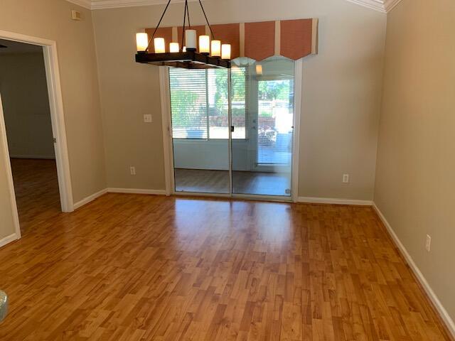 unfurnished room with ornamental molding, wood-type flooring, and a chandelier