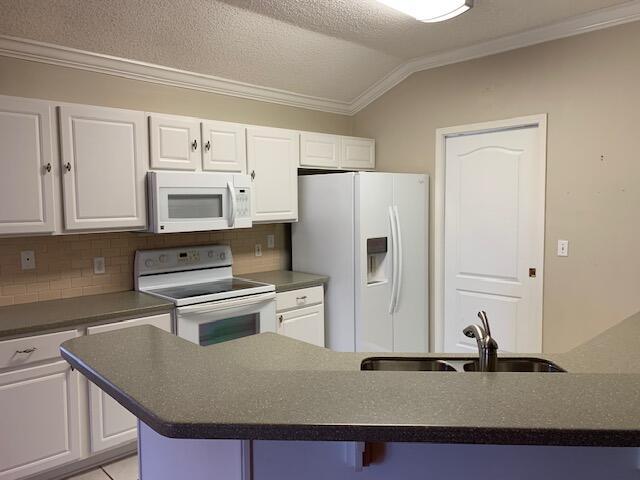 kitchen featuring white cabinetry, sink, white appliances, and a breakfast bar area