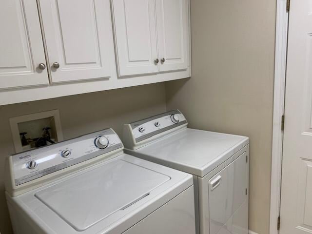 clothes washing area with cabinets and washing machine and dryer