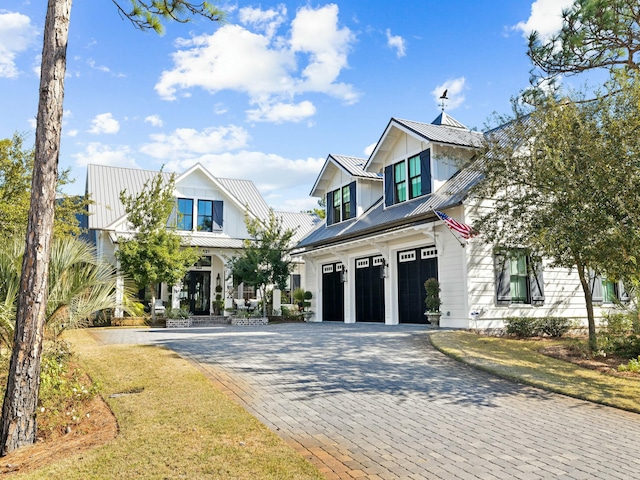 modern inspired farmhouse featuring a garage, metal roof, decorative driveway, and a standing seam roof