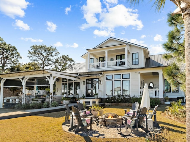 back of house featuring a balcony, a patio area, an outdoor fire pit, and metal roof