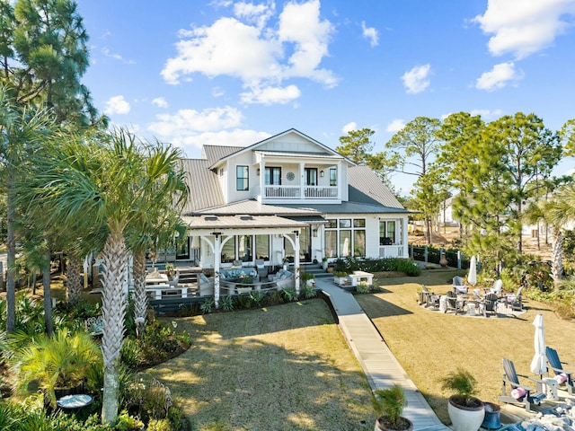 view of front facade featuring metal roof, a patio, a balcony, a fire pit, and a front lawn