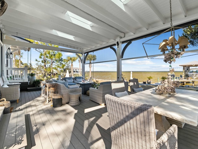 wooden deck with a water view, exterior bar, and an outdoor hangout area