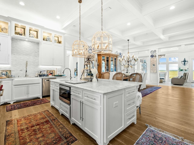 kitchen with glass insert cabinets, white cabinetry, a sink, and an island with sink