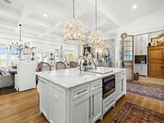 kitchen featuring white cabinetry, a kitchen island with sink, built in microwave, and open floor plan