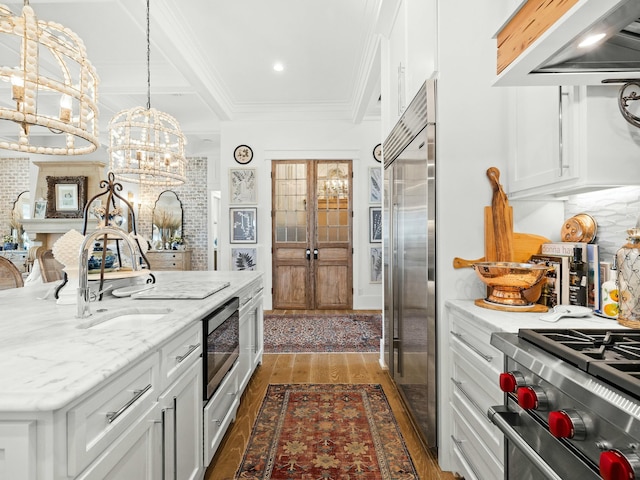 kitchen with dark wood-style flooring, crown molding, high end appliances, white cabinetry, and a sink