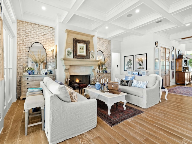 living room featuring visible vents, coffered ceiling, a lit fireplace, light wood-style floors, and beam ceiling