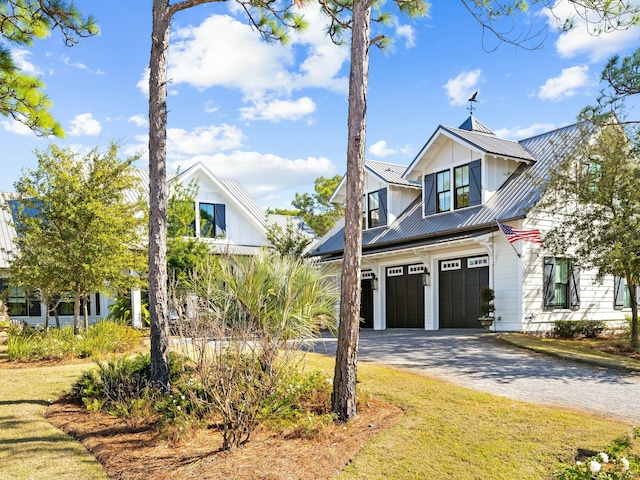 modern inspired farmhouse featuring a front yard, decorative driveway, metal roof, and an attached garage