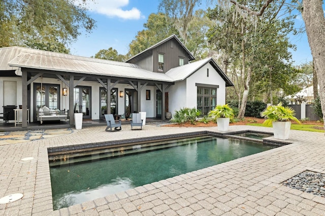 rear view of property with a swimming pool with hot tub, a patio area, and french doors