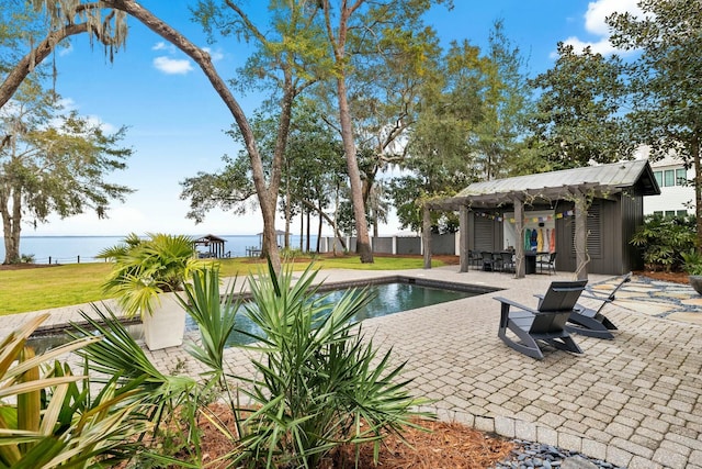 view of swimming pool with a water view, an outbuilding, a yard, exterior bar, and a patio