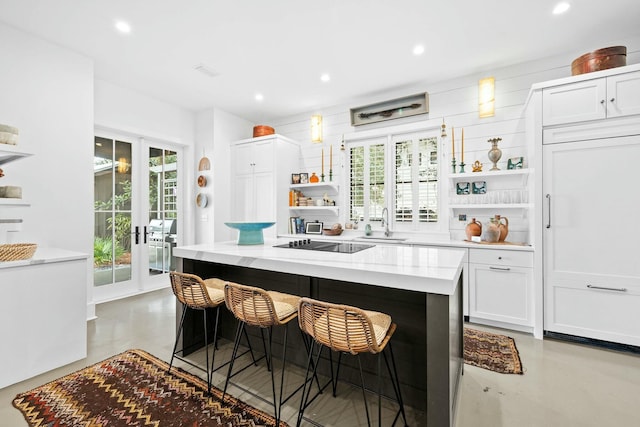 kitchen featuring french doors, sink, a kitchen island, black electric stovetop, and white cabinets