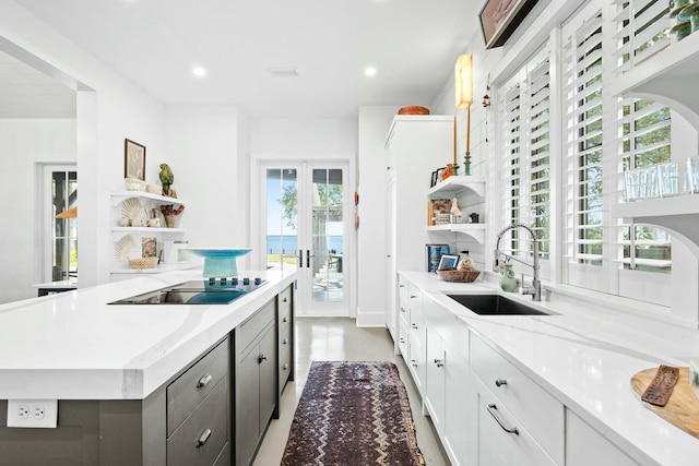 kitchen featuring sink, white cabinets, black electric stovetop, light stone countertops, and french doors