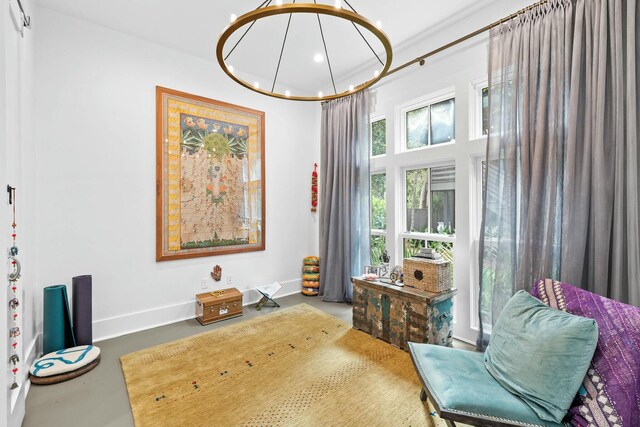 sitting room featuring an inviting chandelier and concrete flooring