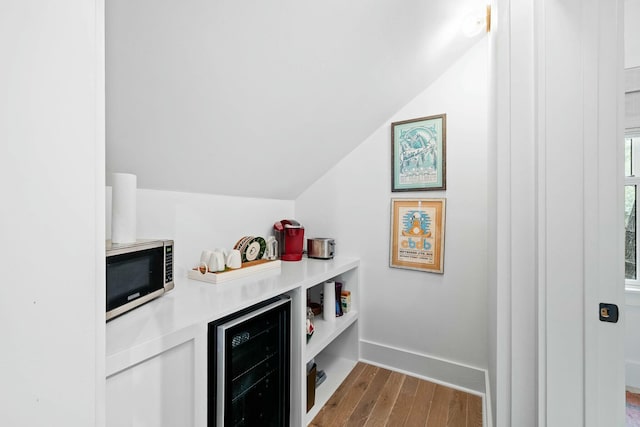 bar featuring lofted ceiling, hardwood / wood-style floors, and beverage cooler