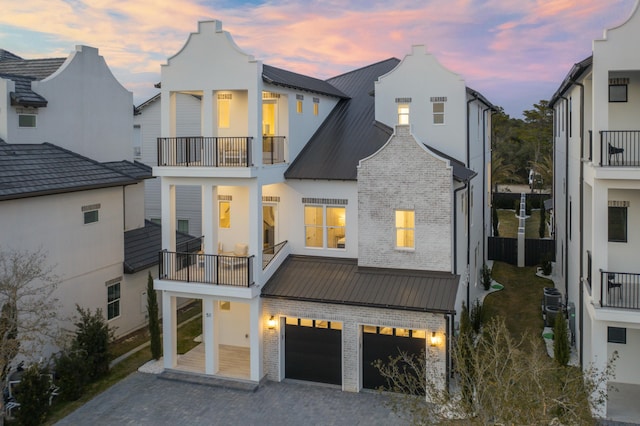 view of front facade featuring a garage, metal roof, a standing seam roof, decorative driveway, and brick siding