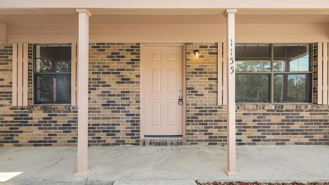 view of exterior entry with covered porch and brick siding