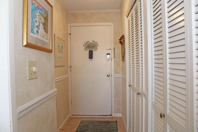 corridor with ornamental molding, wainscoting, and light tile patterned floors