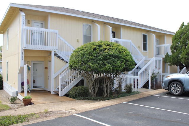 view of property featuring uncovered parking and stairway
