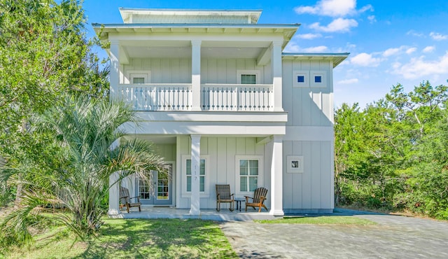 back of house with a balcony, covered porch, and board and batten siding