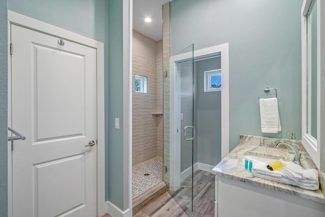 full bath featuring a stall shower, baseboards, wood finished floors, and vanity