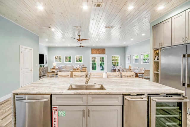 kitchen featuring wine cooler, appliances with stainless steel finishes, open floor plan, light stone countertops, and french doors