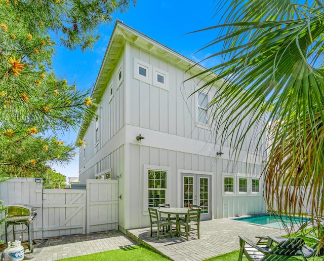 back of property featuring french doors, a gate, a fenced in pool, board and batten siding, and a patio area