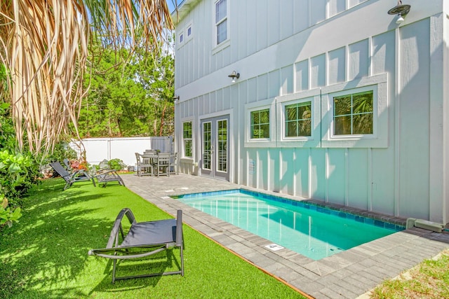 view of pool featuring a fenced in pool, a fenced backyard, a yard, french doors, and a patio area