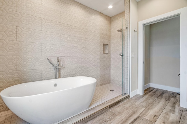 bathroom featuring recessed lighting, wood finish floors, baseboards, a freestanding bath, and a shower stall