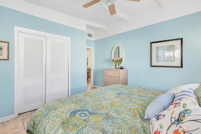 tiled bedroom with ceiling fan, beam ceiling, and a closet