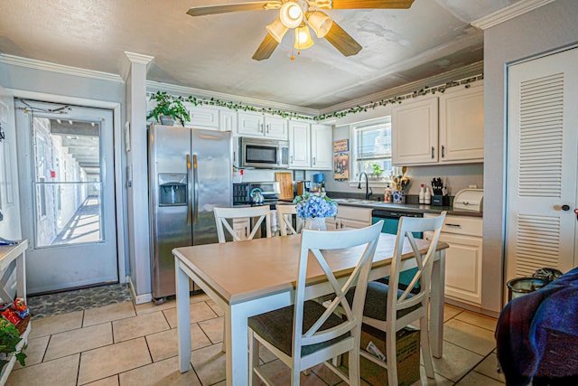 kitchen with sink, a breakfast bar area, ornamental molding, appliances with stainless steel finishes, and white cabinets