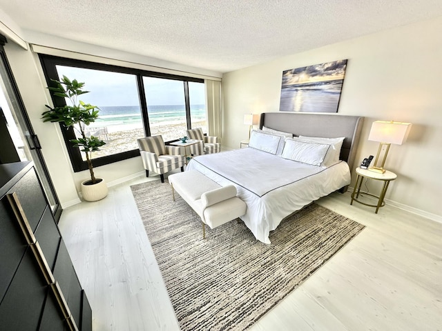 4045 Beachside One Dr # 4045, Miramar Beach, FL 32550 - bedroom with wood finished floors, a textured ceiling, view of water and beach, and baseboards