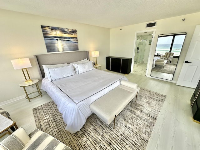 4045 Beachside One Dr # 4045, Miramar Beach, FL 32550 - bedroom with light wood finished floors, a textured ceiling, baseboards, and ensuite bathroom
