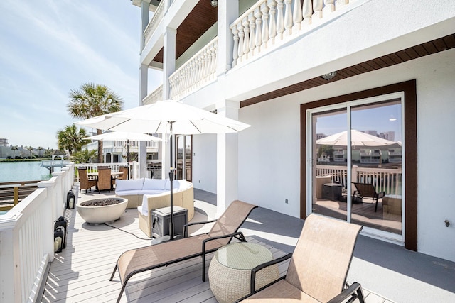 wooden deck with an outdoor living space with a fire pit and a water view