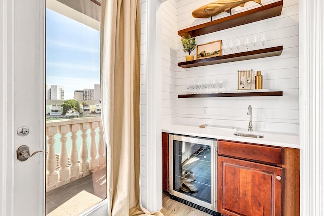 bar featuring wine cooler, sink, and light hardwood / wood-style flooring