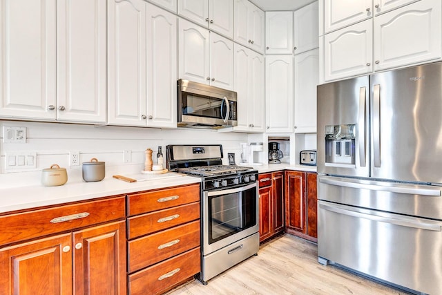 kitchen with appliances with stainless steel finishes, light hardwood / wood-style floors, and white cabinets