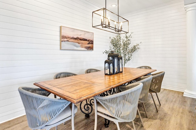 dining area with ornate columns, an inviting chandelier, and light hardwood / wood-style floors