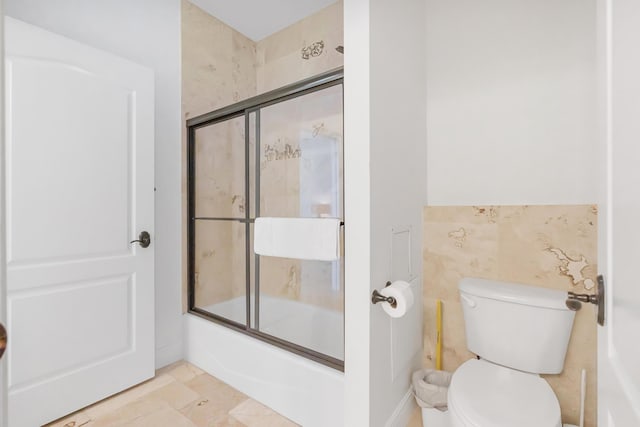 full bath with toilet and shower / bath combination with glass door