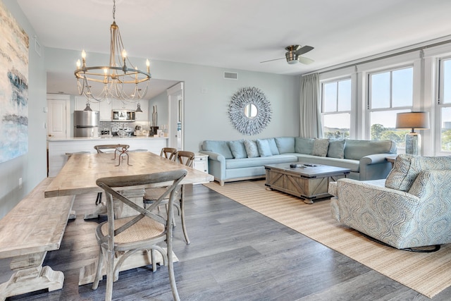 living room with ceiling fan with notable chandelier and light hardwood / wood-style flooring