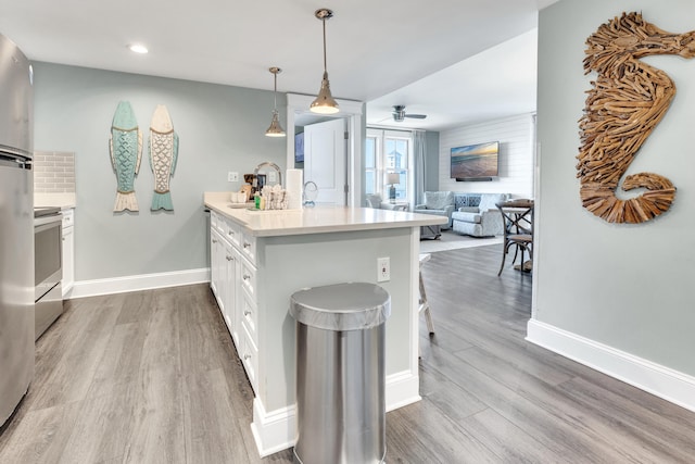 kitchen featuring a kitchen bar, decorative light fixtures, light hardwood / wood-style flooring, kitchen peninsula, and white cabinets