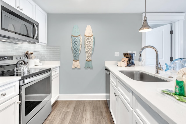 kitchen featuring sink, white cabinetry, tasteful backsplash, appliances with stainless steel finishes, and hardwood / wood-style floors