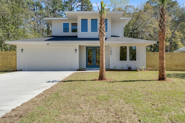 view of front of house featuring a front yard, fence, driveway, french doors, and a garage