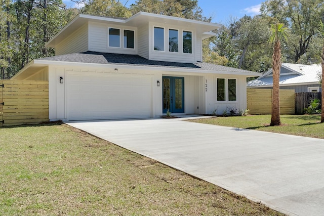 view of front of house featuring a front yard, fence, driveway, french doors, and a garage