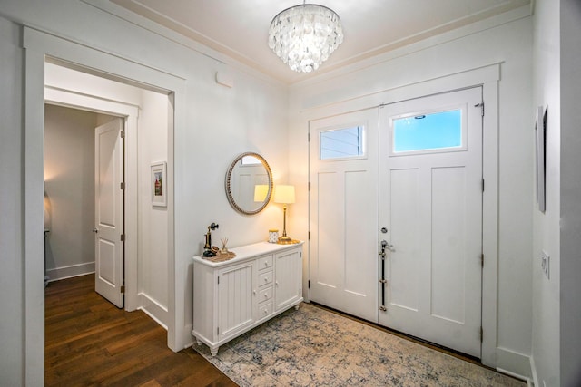 entryway featuring crown molding, dark wood-type flooring, and an inviting chandelier