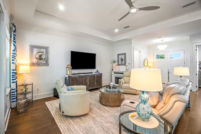 living room with hardwood / wood-style flooring, ceiling fan, and a tray ceiling