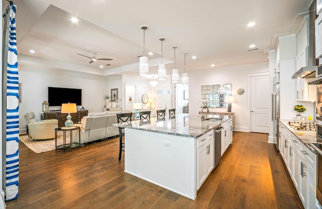 kitchen featuring a large island, a breakfast bar, light stone countertops, white cabinets, and decorative light fixtures