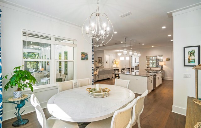 dining space with crown molding, dark hardwood / wood-style floors, a chandelier, and sink