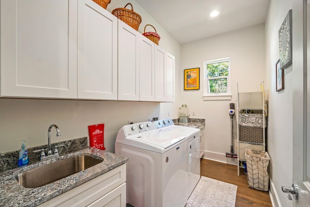 clothes washing area with cabinets, sink, dark wood-type flooring, and washing machine and clothes dryer