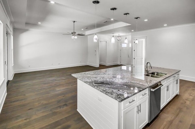 kitchen featuring sink, stone counters, an island with sink, white cabinets, and decorative light fixtures